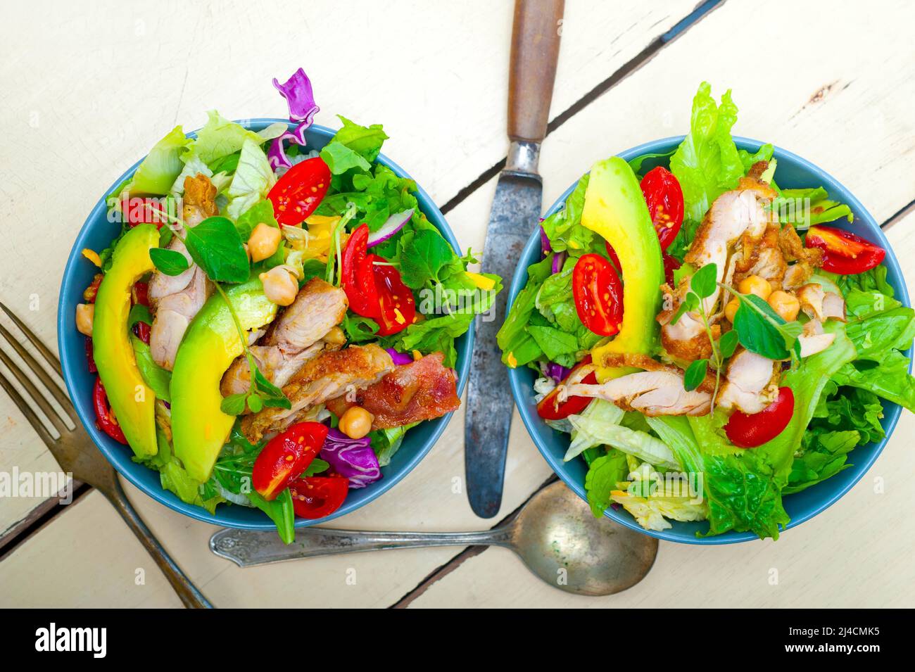 Fresh and healthy chicken avocado salad over rustic wood table stock