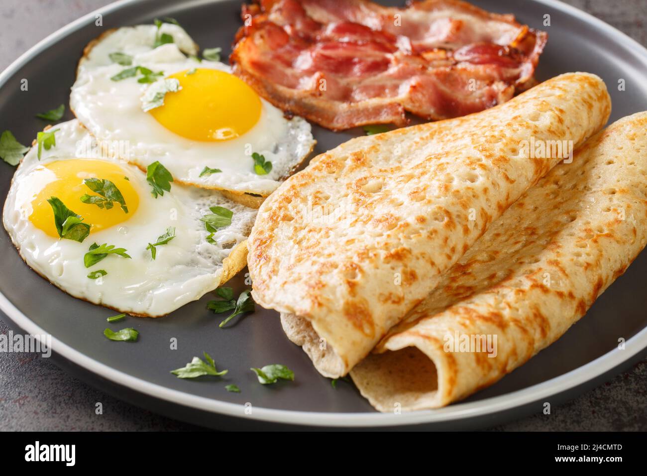 Staffordshire oatcakes with bacon and fried eggs close-up in a plate on the table. Horizontal Stock Photo