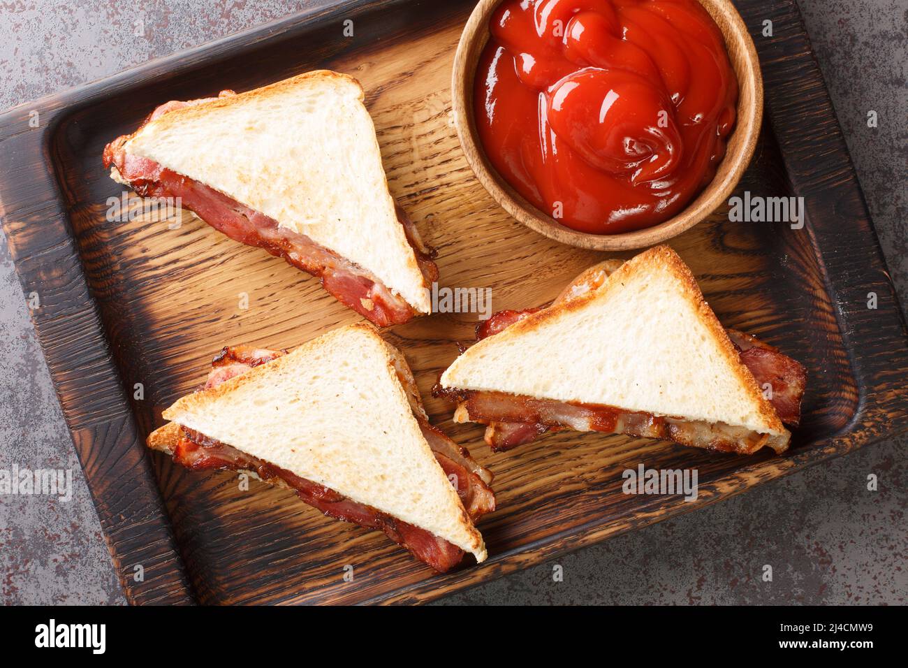 English Bacon Sandwich closeup in the wooden tray on the table. Horizontal top view from above Stock Photo