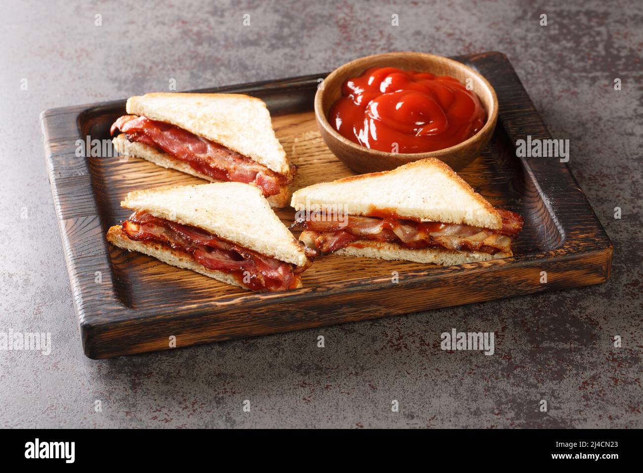 English Bacon Sandwich closeup in the wooden tray on the table. Horizontal Stock Photo