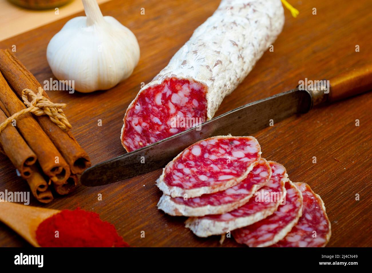 Traditional Italian salame cured sausage sliced on a wood board Stock