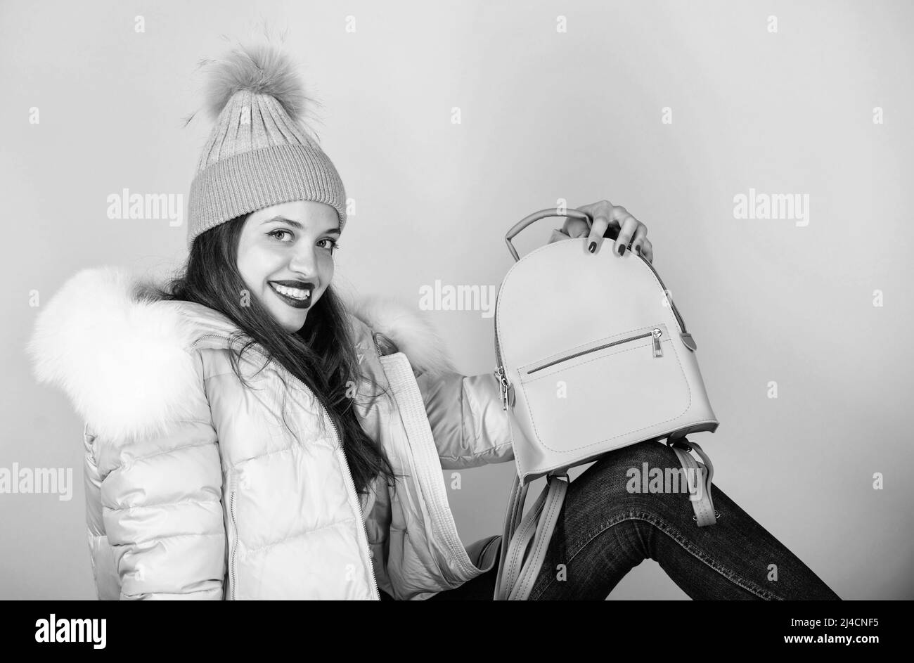 students life. girl in puffed coat. faux fur fashion. flu and cold season. Leather bag fashion. woman in beanie hat with backpack. warm winter Stock Photo