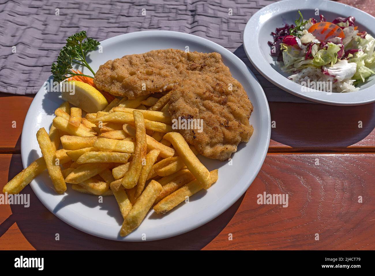 Wiener Schnitzel with french fries and salad served in a garden restaurant, Franconia, Bavaria, Germany Stock Photo