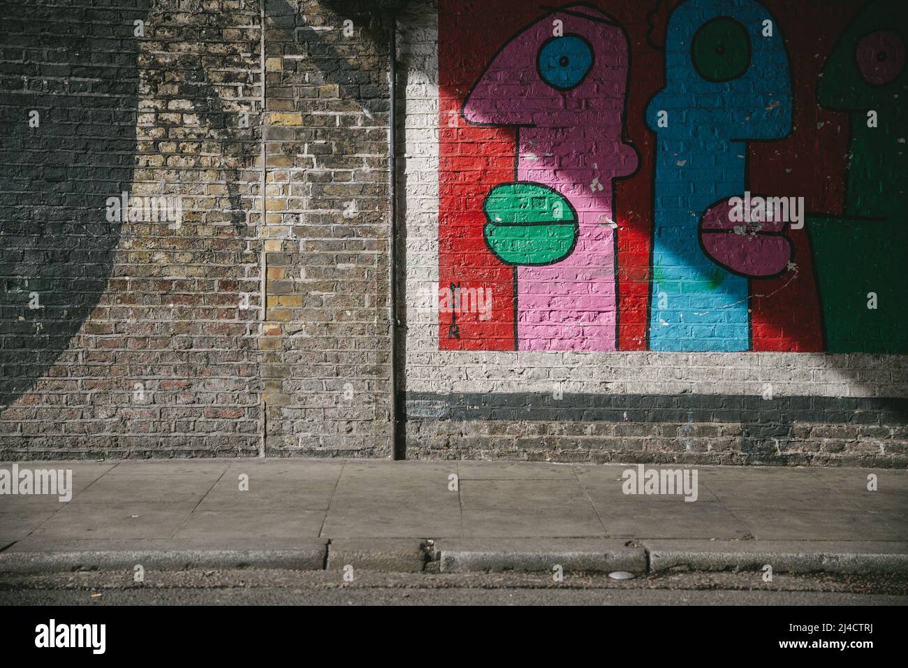 Shoreditch, London, UK - April 14, 2016: Some colourful East London Street Art, caught in some shadow. Stock Photo