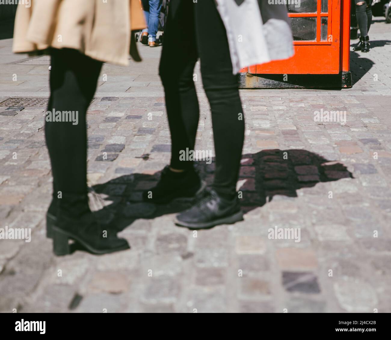 Covent Garden, London, UK - April 12, 2016: Two people (waist down) can be seen standing/interacting on a cobbled London street. Stock Photo