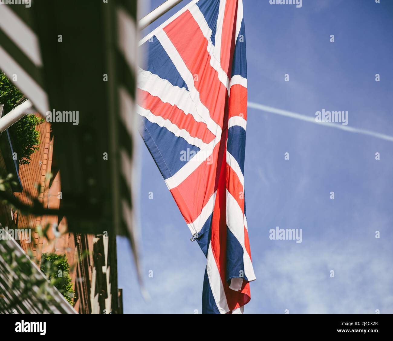 Holborn, London, UK - April 12, 2016: A union jack flag hangs, on a buildings exterior, with a blue summer sky backdrop. Stock Photo