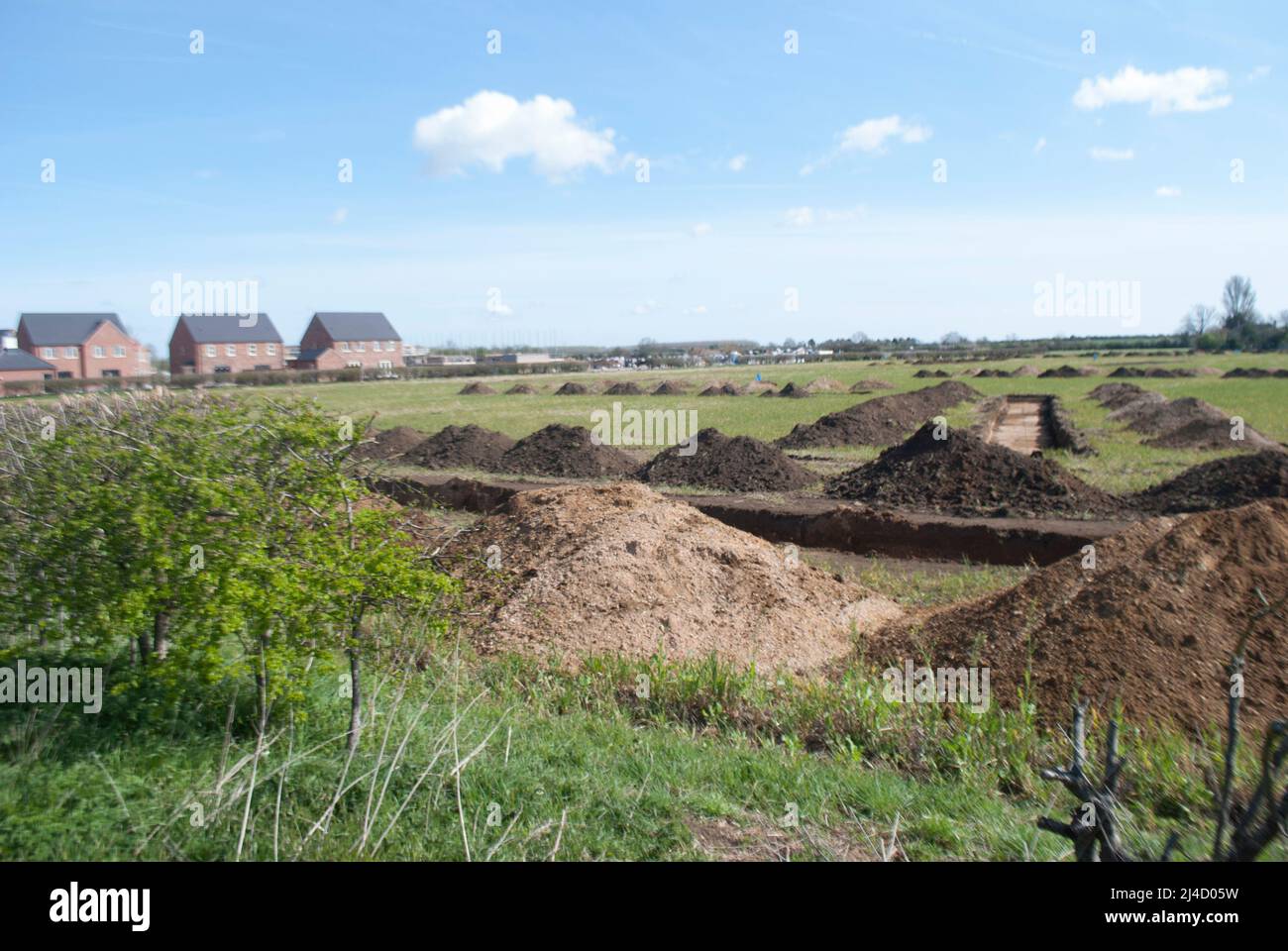 Trenches dug in field for archaeological survey with new build houses