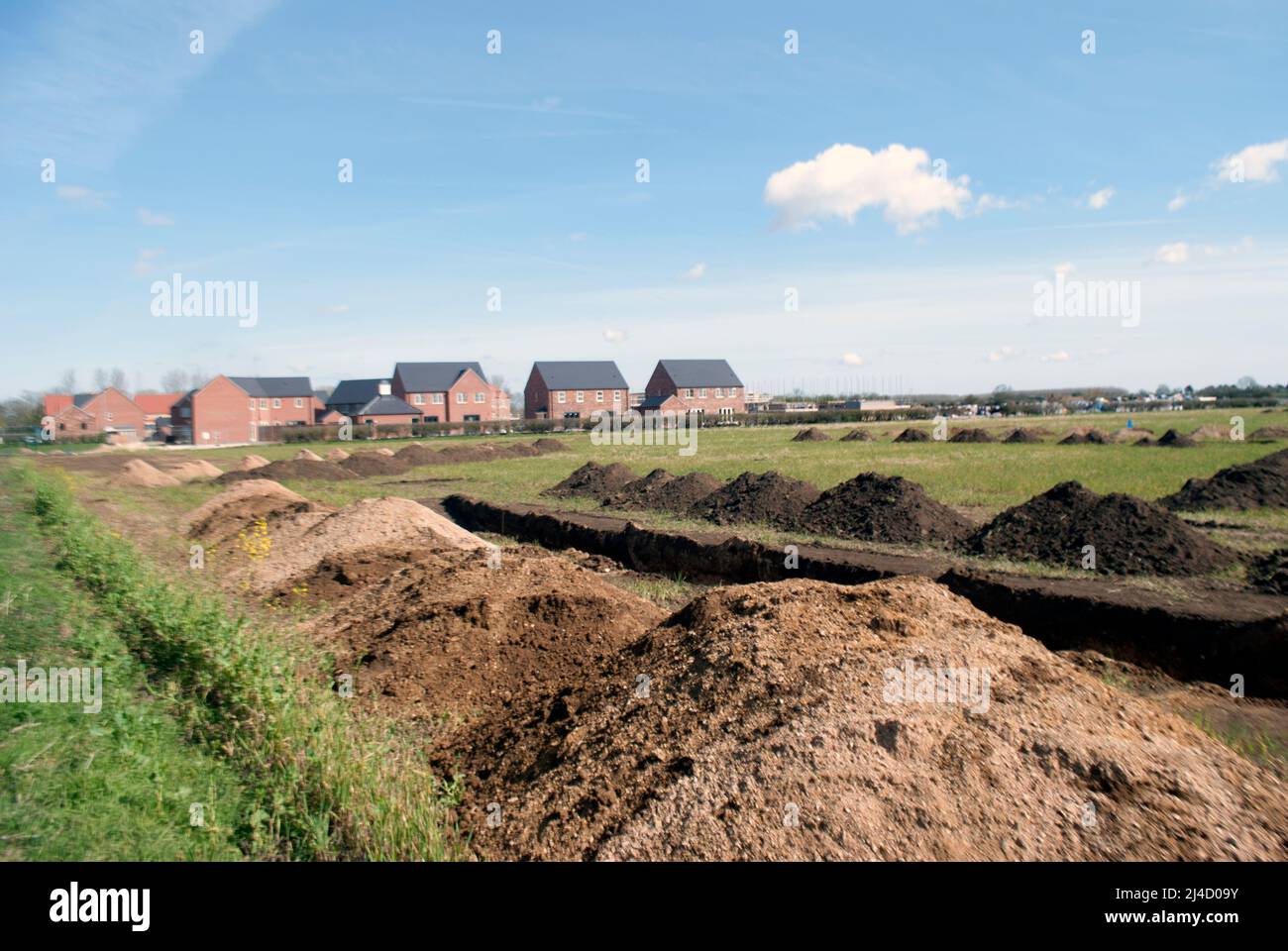Trenches dug in field for archaeological survey with new build houses