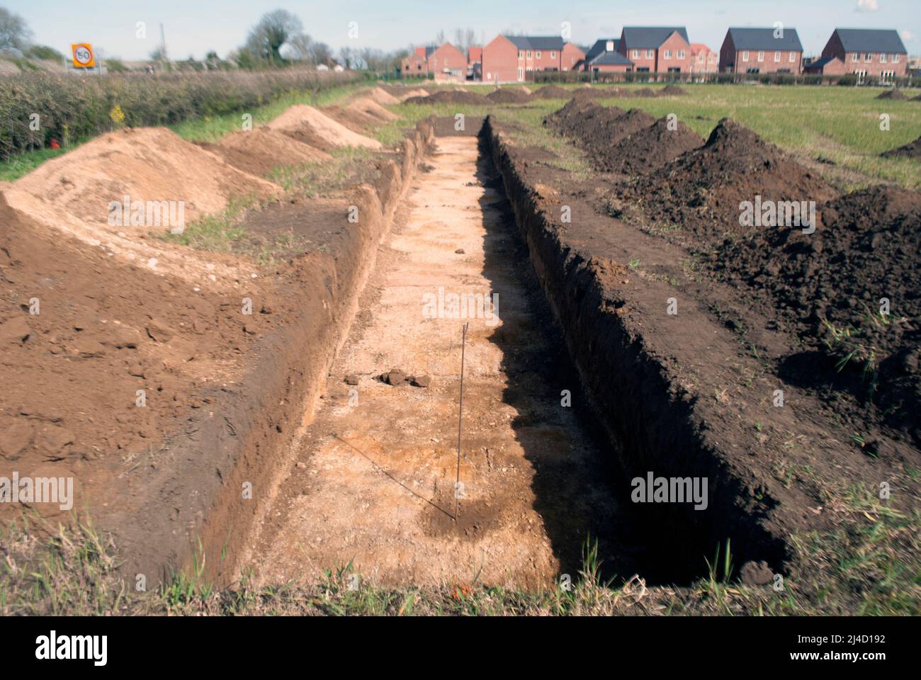Trenches dug in field for archaeological survey with new build houses