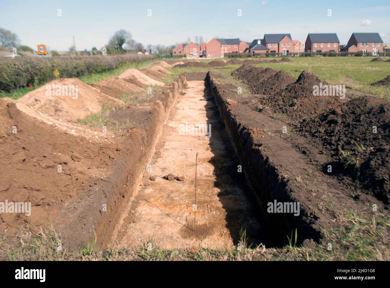 Trenches dug in field for archaeological survey with new build houses