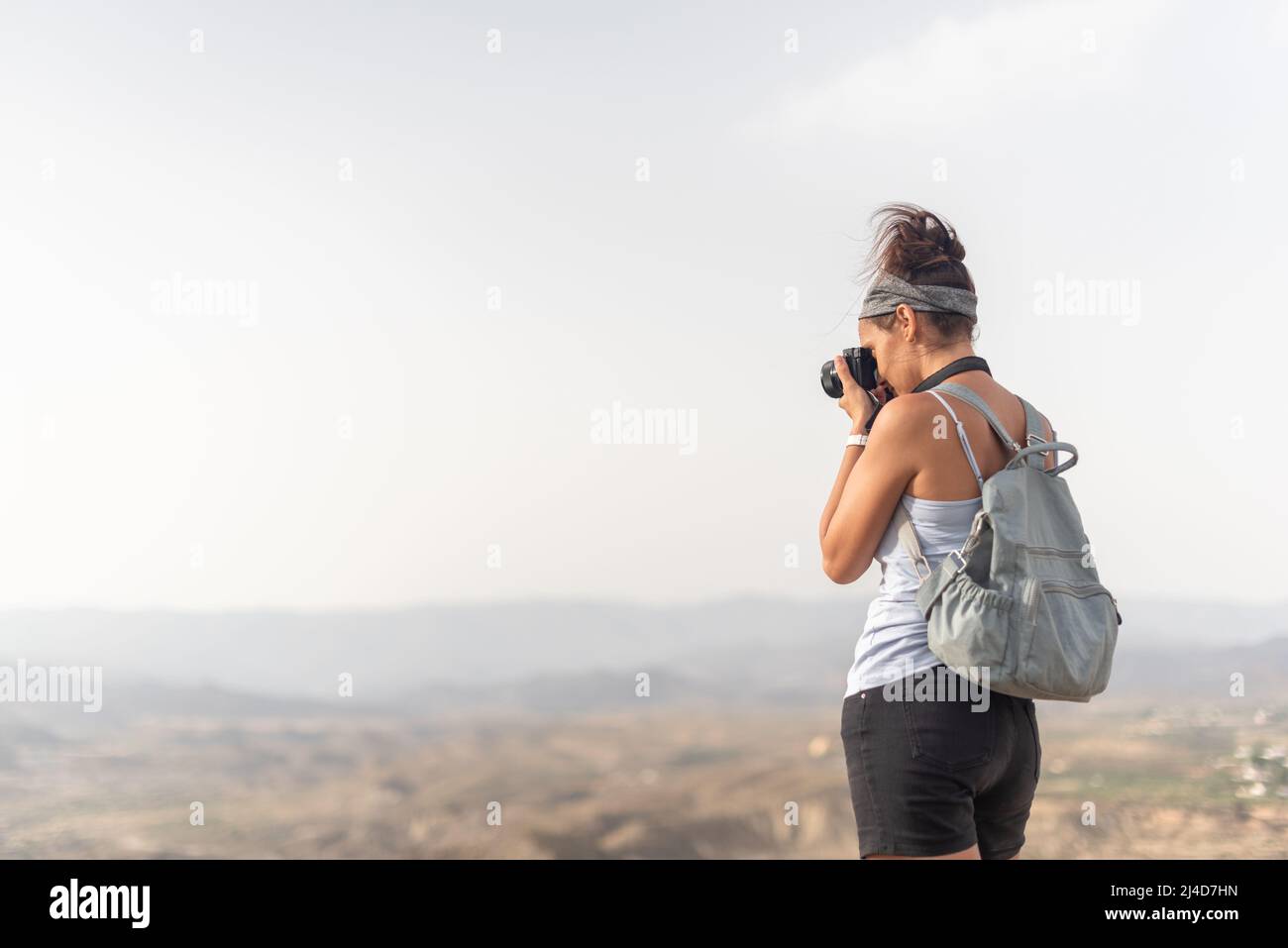 Anonymous woman with backpack taking photo in mountains Stock Photo