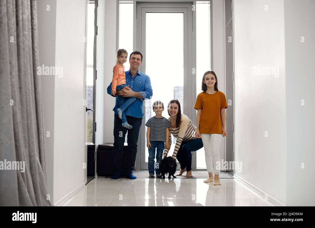 Excited kids arriving home with their parents. Children returning home with parents mom and dad, smiling cute children brother and sisters, entering a Stock Photo