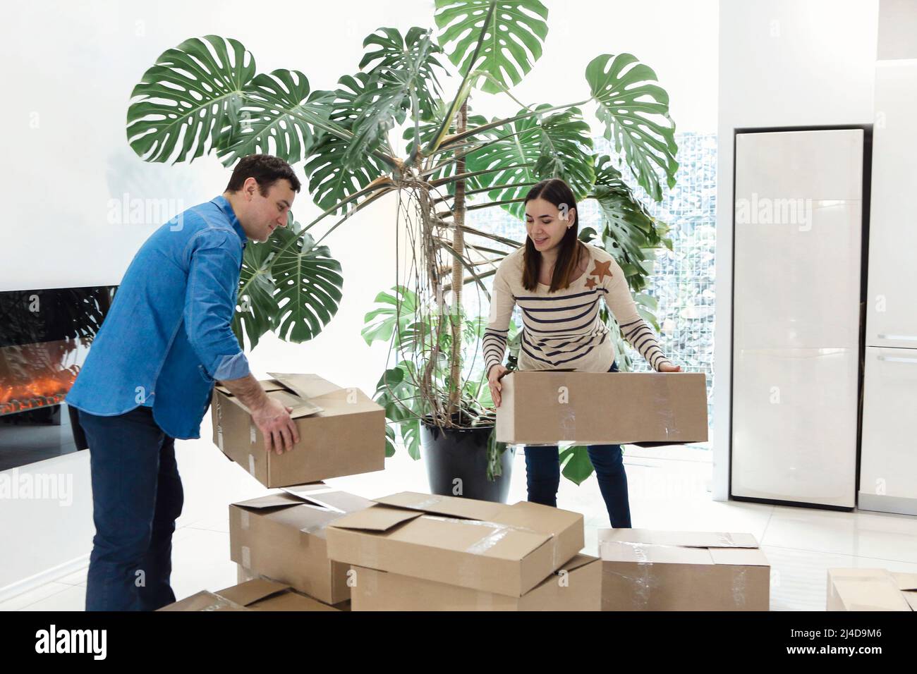 Happy couple with cardboard boxes in new home. Woman holding keys. New home and happiness concept. Mortgage for the family Stock Photo