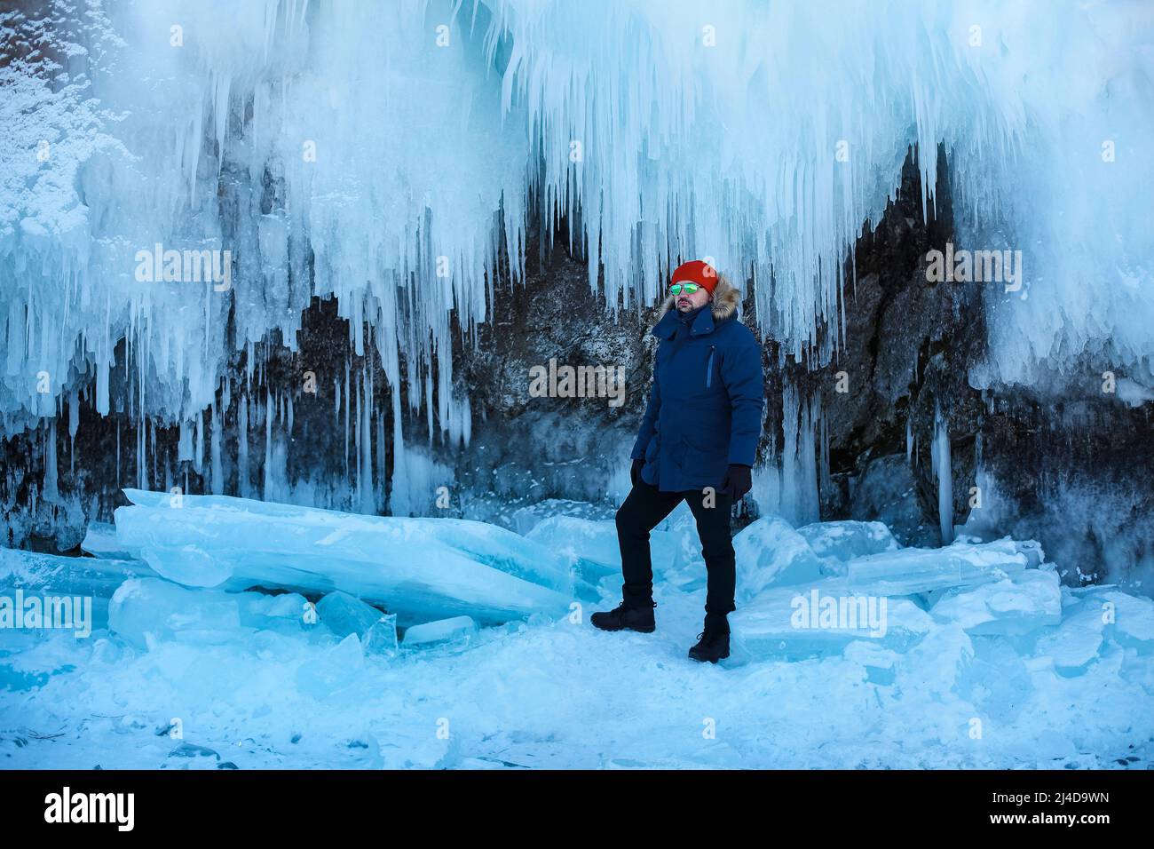 Travel and winter holiday. Lake Baikal. Portrait of the man tourist in red cap and blue jacket wearing sunglasses on ice Stock Photo