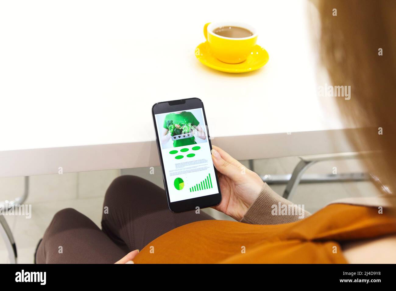 Pregnant woman holding smartphone using pregnancy tracker app on mobile