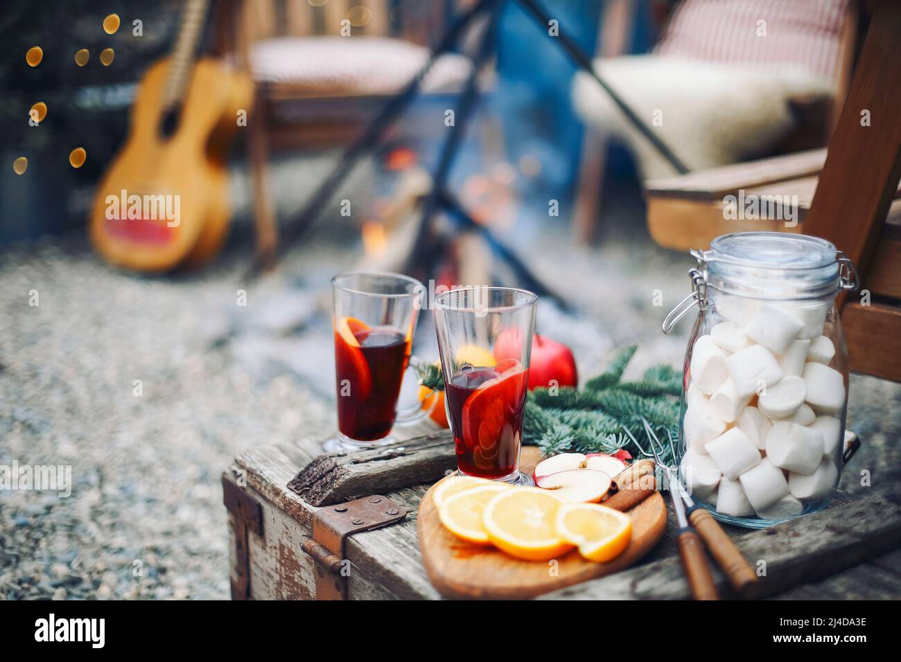 Two glasses of hot mulled wine drink with citrus, apples, cinnamon sticks, cloves and anise on wooden table background. Outdoors Stock Photo