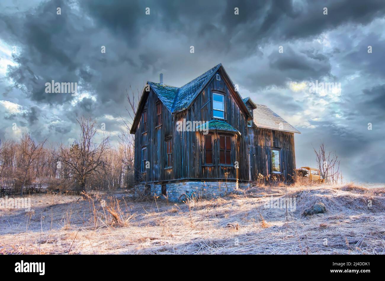 An old abandoned spooky looking farmhouse in winter on a farm yard in rural Canada Stock Photo