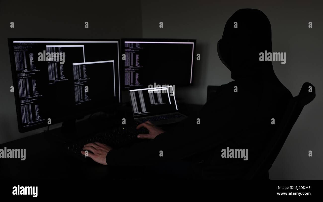 hacker in the dark working on multiple devices Stock Photo
