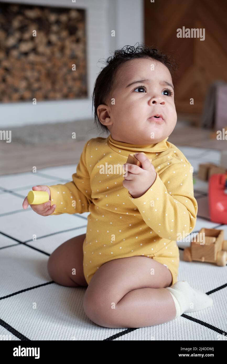 Vertical full body shot of lovely curious baby wearing yellow clothes