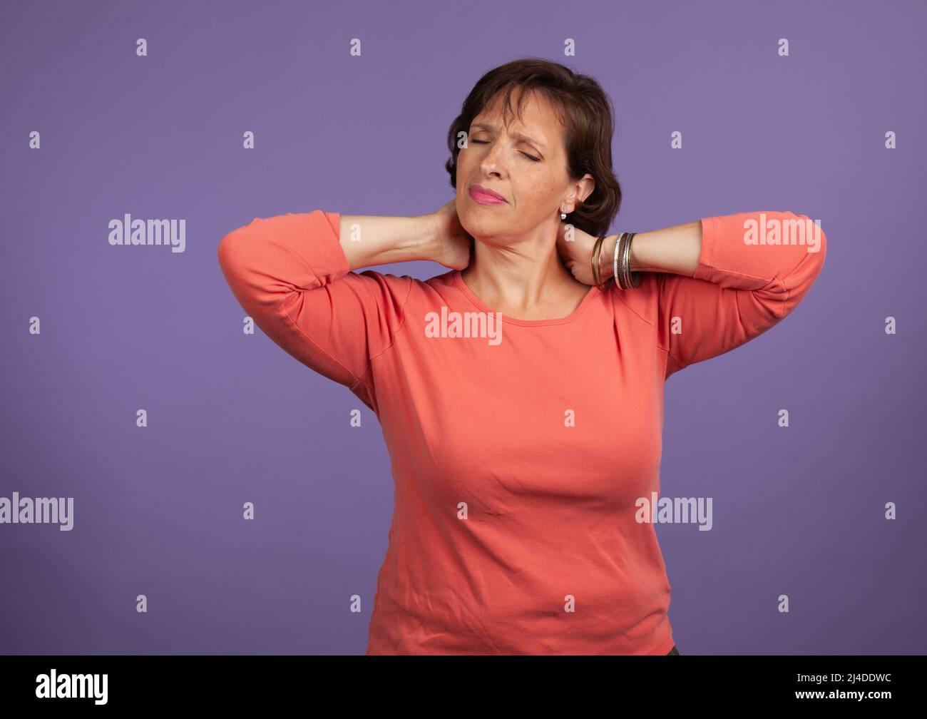 Middle Aged woman with neck and shoulder pain holding her neck  and making a pained expression. Chronic Pain concept image. Stock Photo
