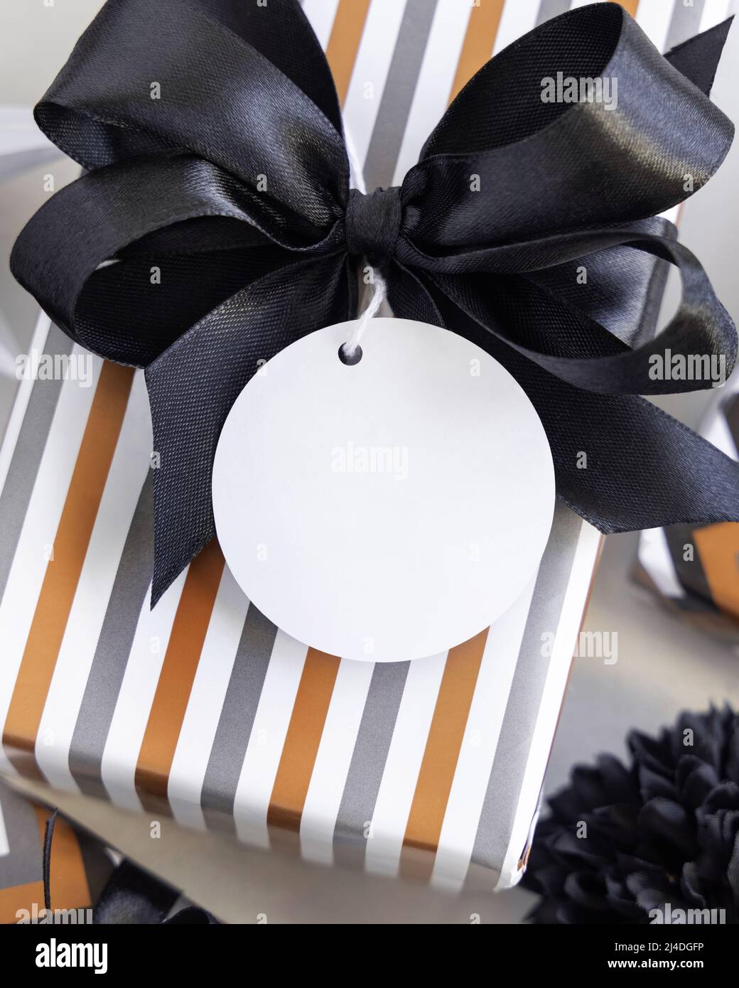 Present with round blank gift tag and black bow close up. Gift boxes ...