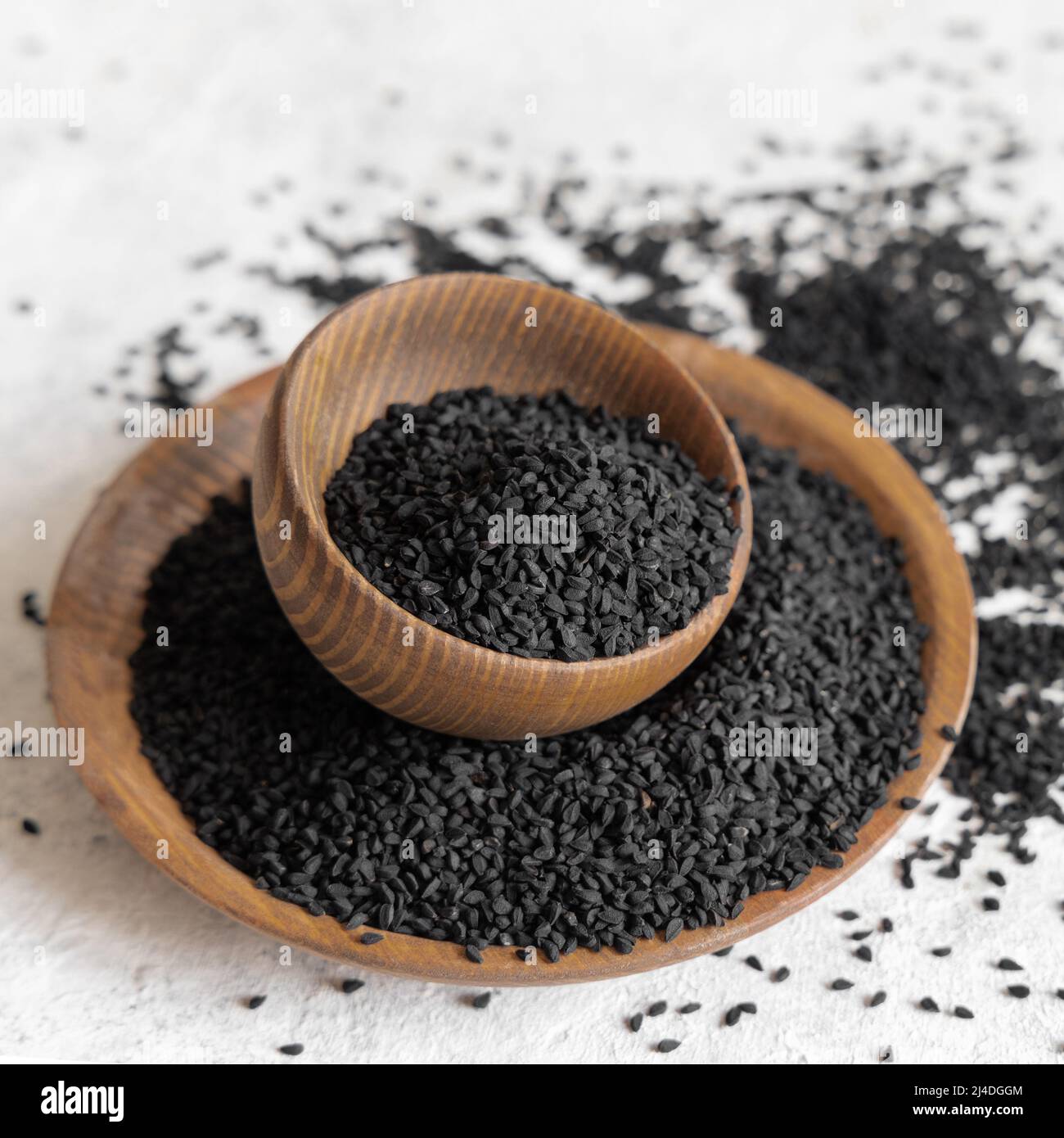 Indian spice Black cumin (nigella sativa or kalonji) seeds in wooden bowls close up. Traditional medicine, healthy and vegetarian food concept. Stock Photo