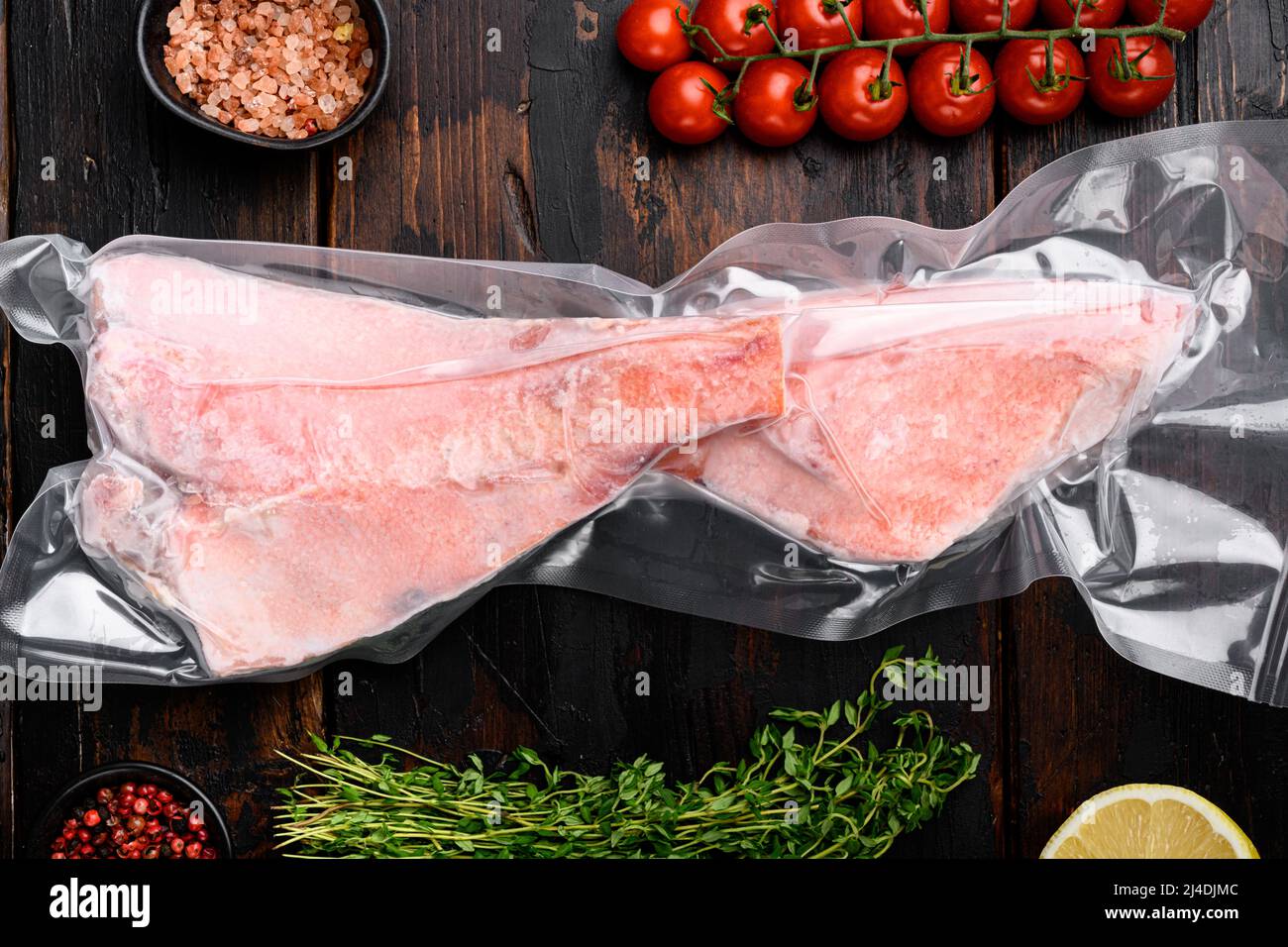 Sea bass frozen pack fish meat, with herbs, on old dark wooden table ...
