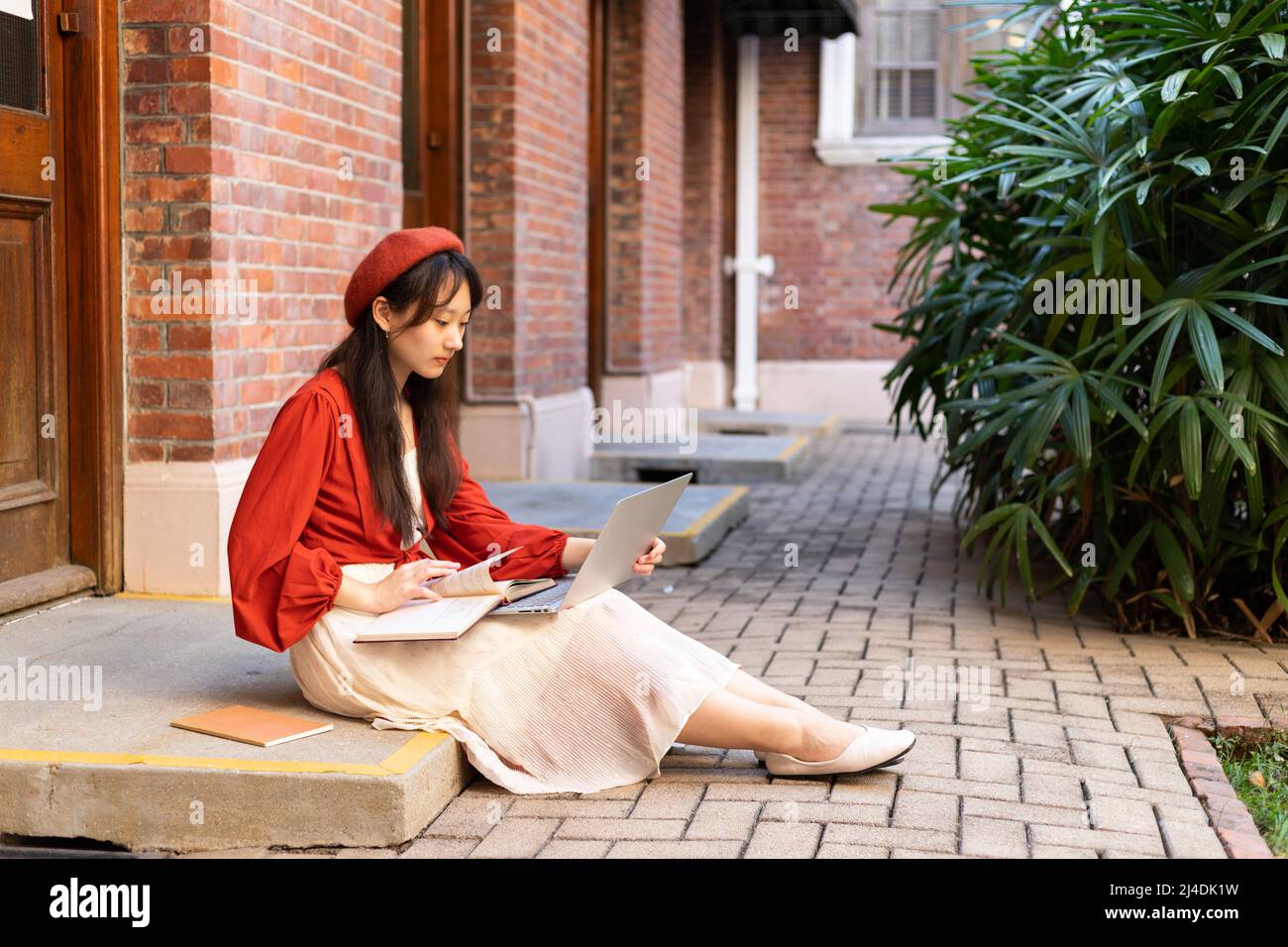 Happy stylish female young university students sit on doorway to use ...