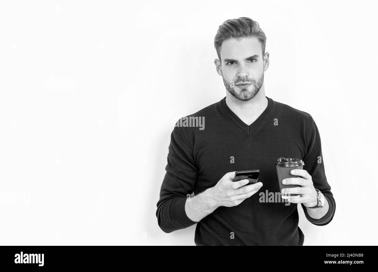 Caffeine and smartphone addiction. Handsome man use phone drinking coffee. Addiction to technology Stock Photo