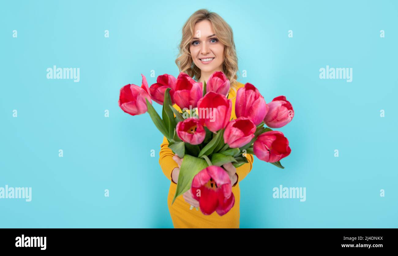 smiling young woman with spring tulip flowers on blue background. march 8 Stock Photo