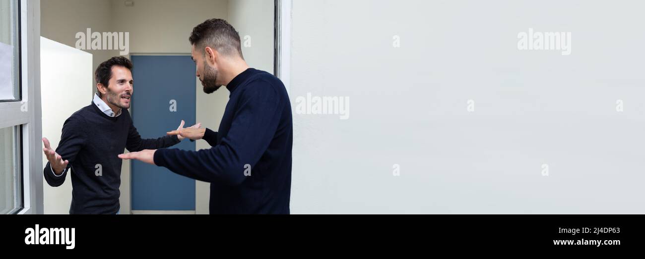 Two Young Men Standing At The Door Entrance Quarreling With Each Other Stock Photo