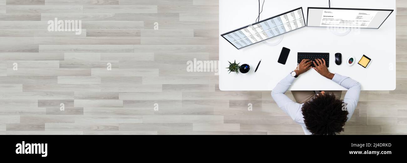 Looking At Invoice And Spreadsheet On Computer At Work Stock Photo