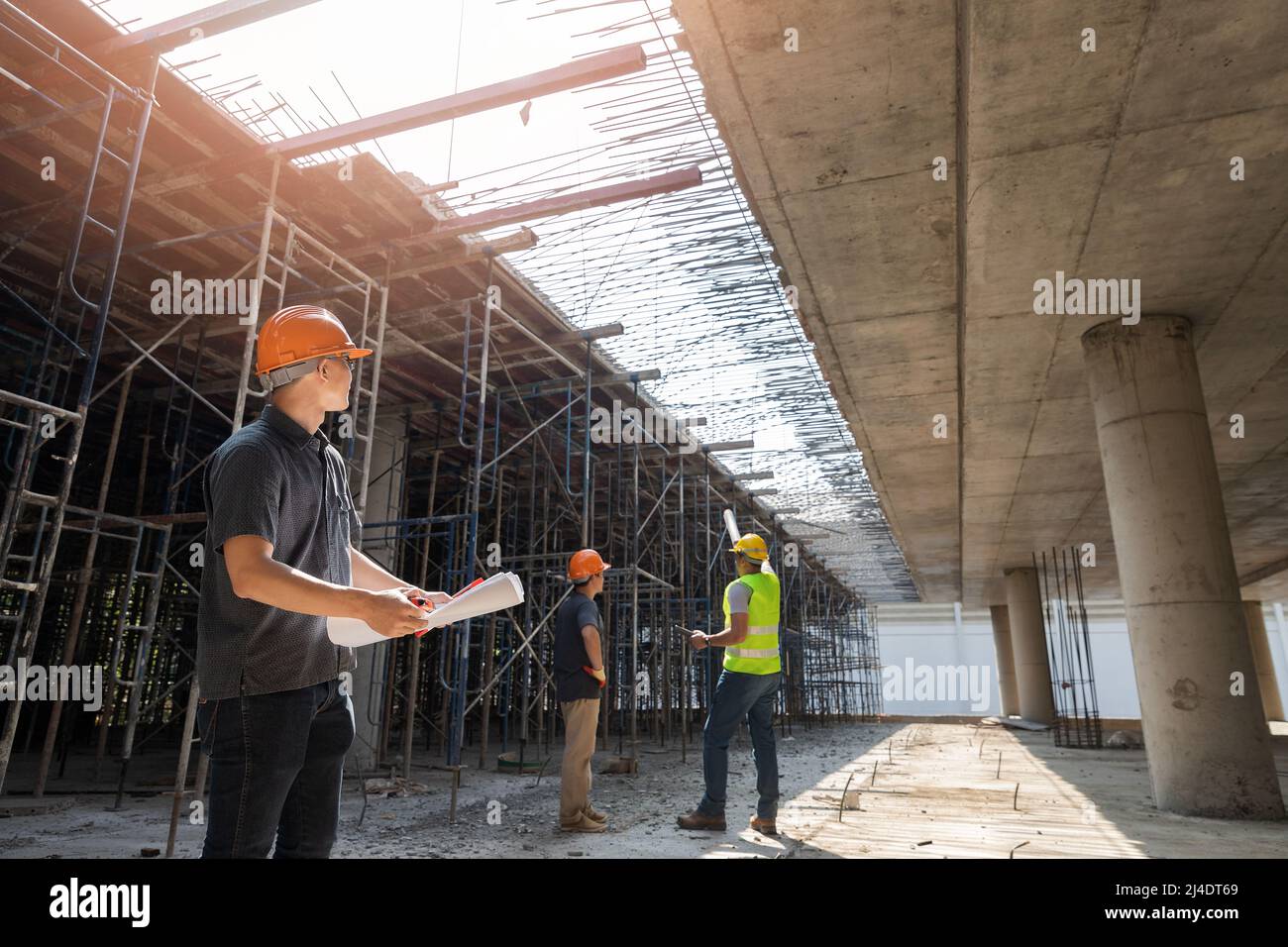 Architect, Engineer, Contractor, or Construction manager holding digital tablet standing with a group of worker at a construction site. Stock Photo