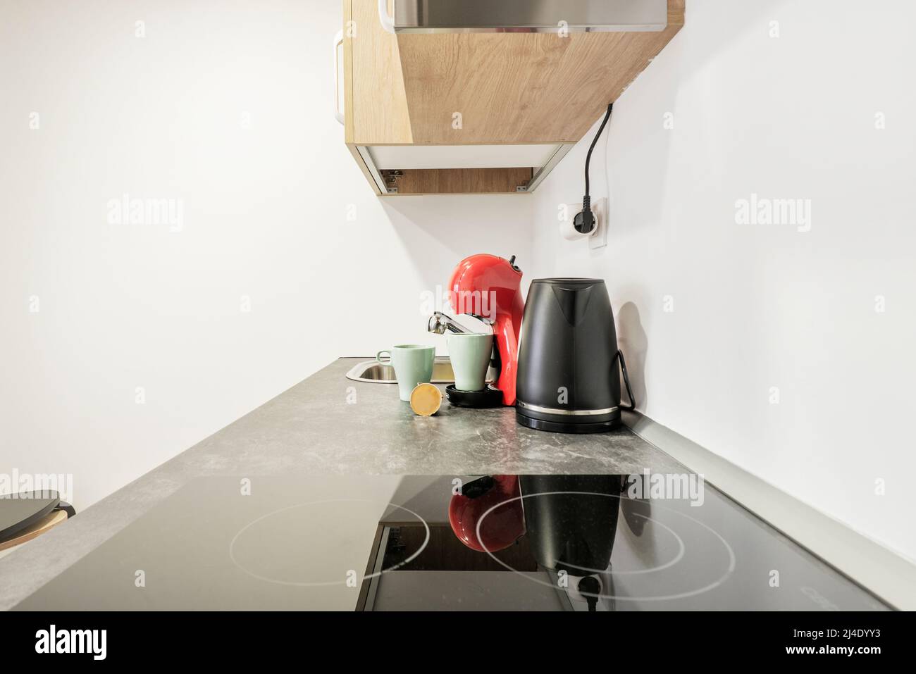 A kitchen countertop with a black ceramic hob next to a water whirlpool and a capsule coffee machine Stock Photo