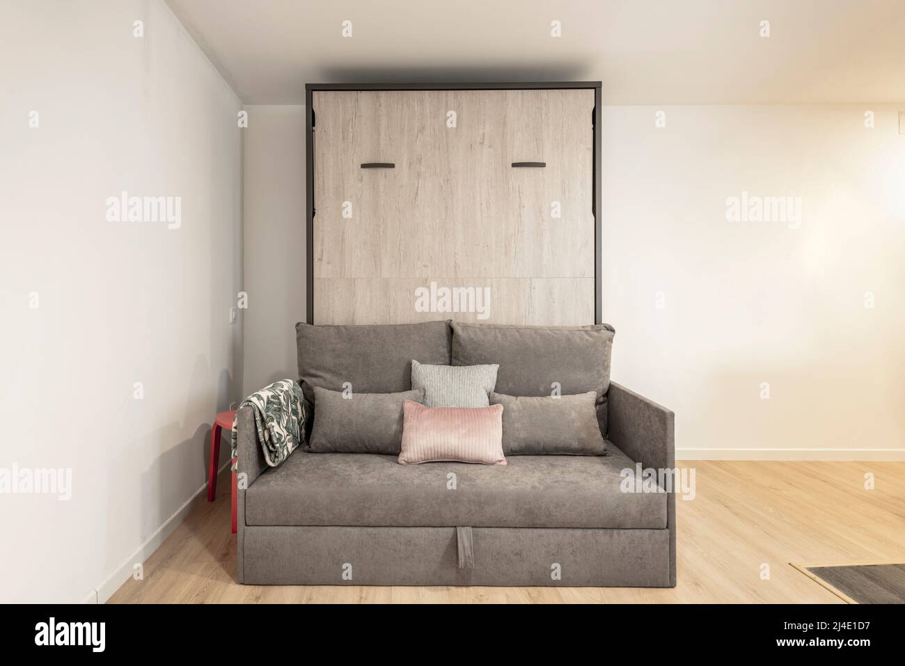 Rollaway bed inside sofa with cushions in shortterm rental studio with