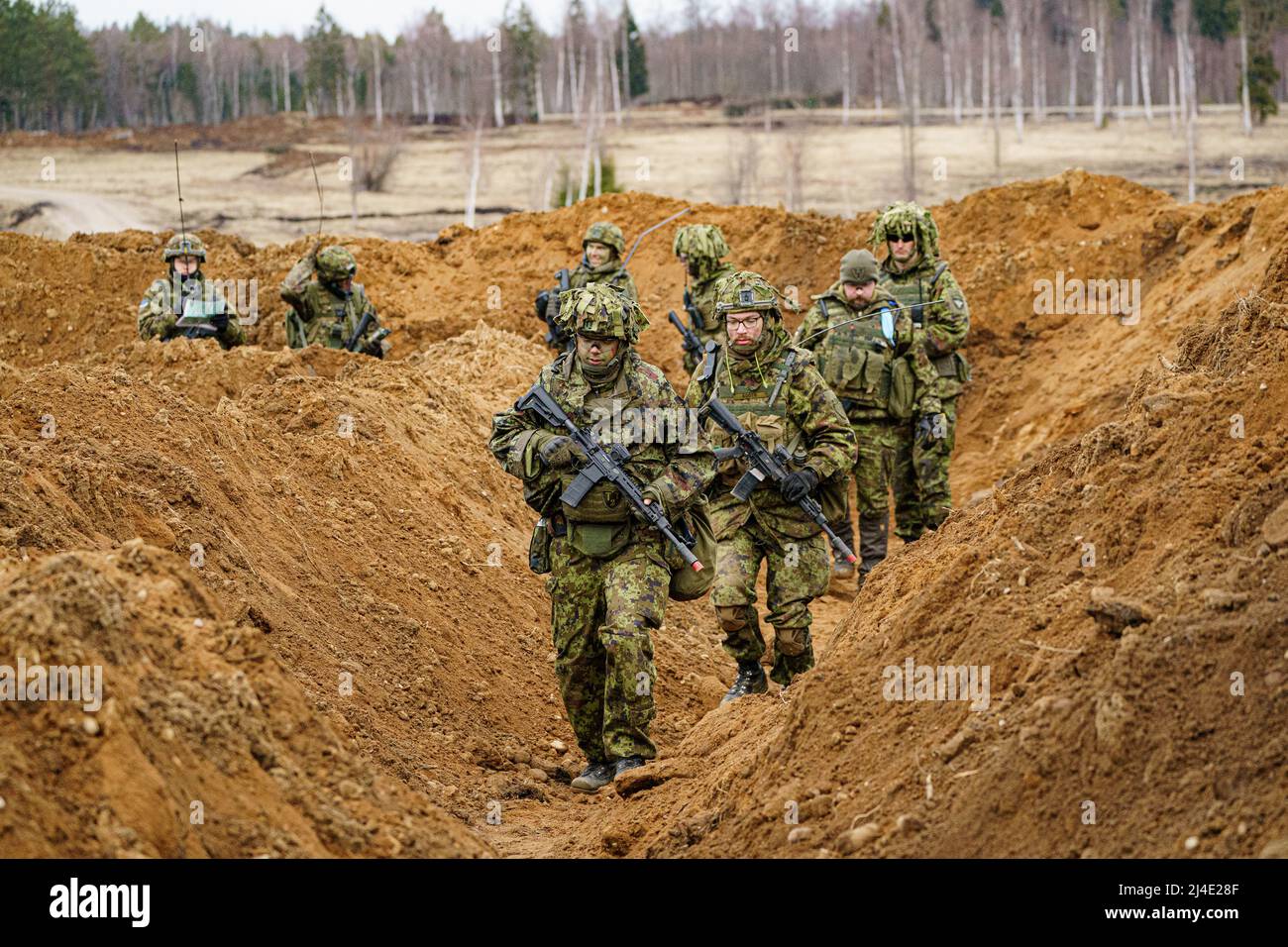 Estonian soldiers advance along a trench as they defend a dug-in position from attacking British armour and infantry in the Tapa central military training area in Estonia on NATO exercise Bold Dragon alongside Danish and French forces. Picture date: Thursday April 14, 2022. Stock Photo