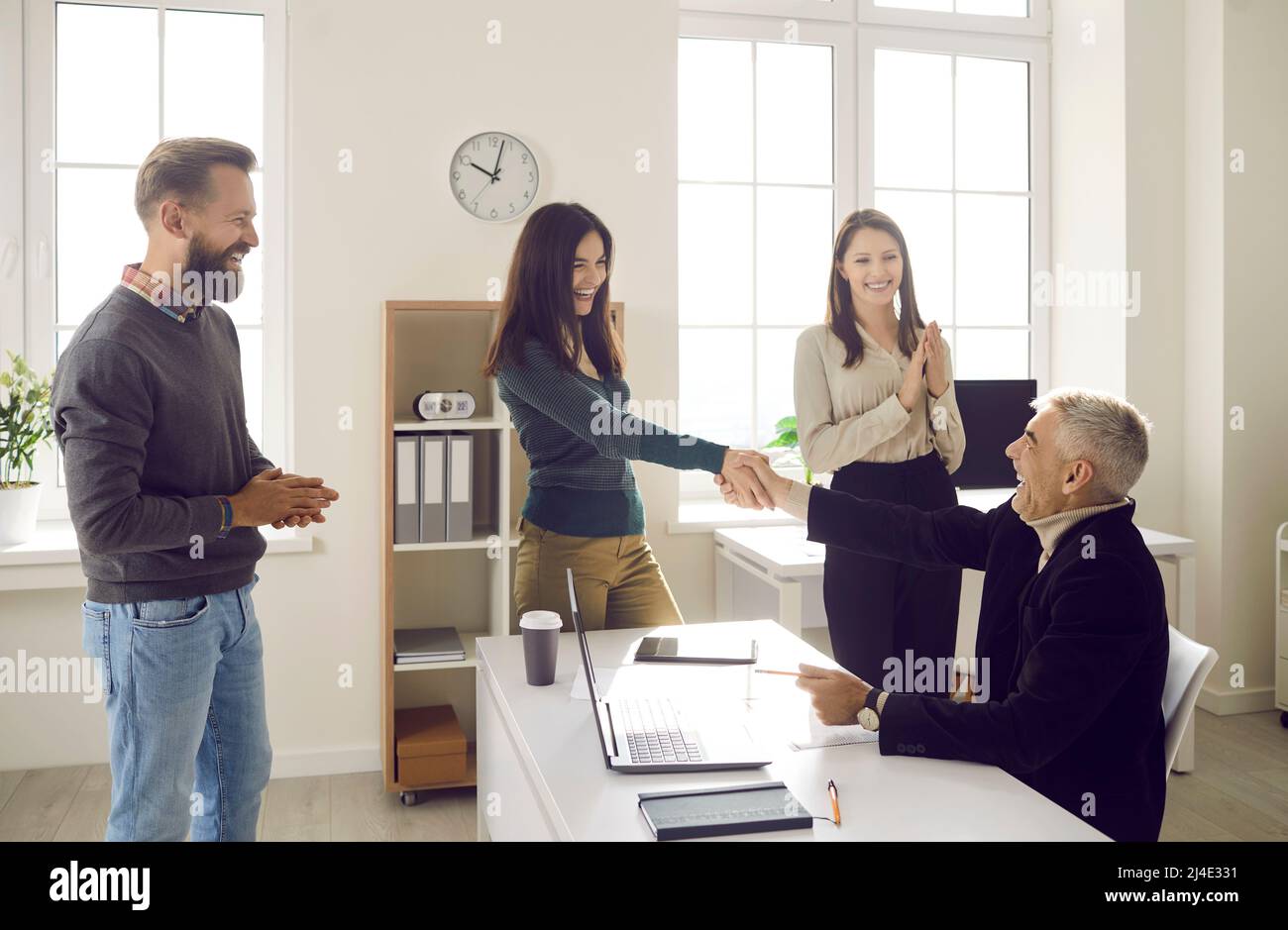 Happy businesswoman greeting aged colleague with promotion Stock Photo