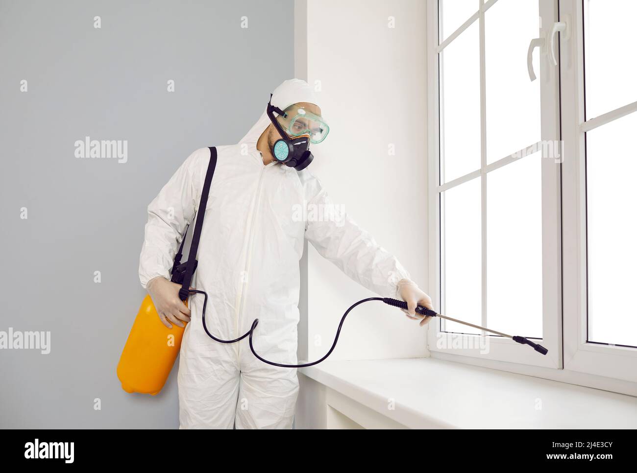 Pest control exterminator in suit and mask spraying insecticide over