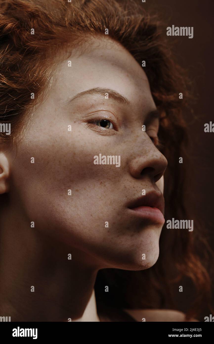 Close-up of young woman with red hair and freckles on her face having ...