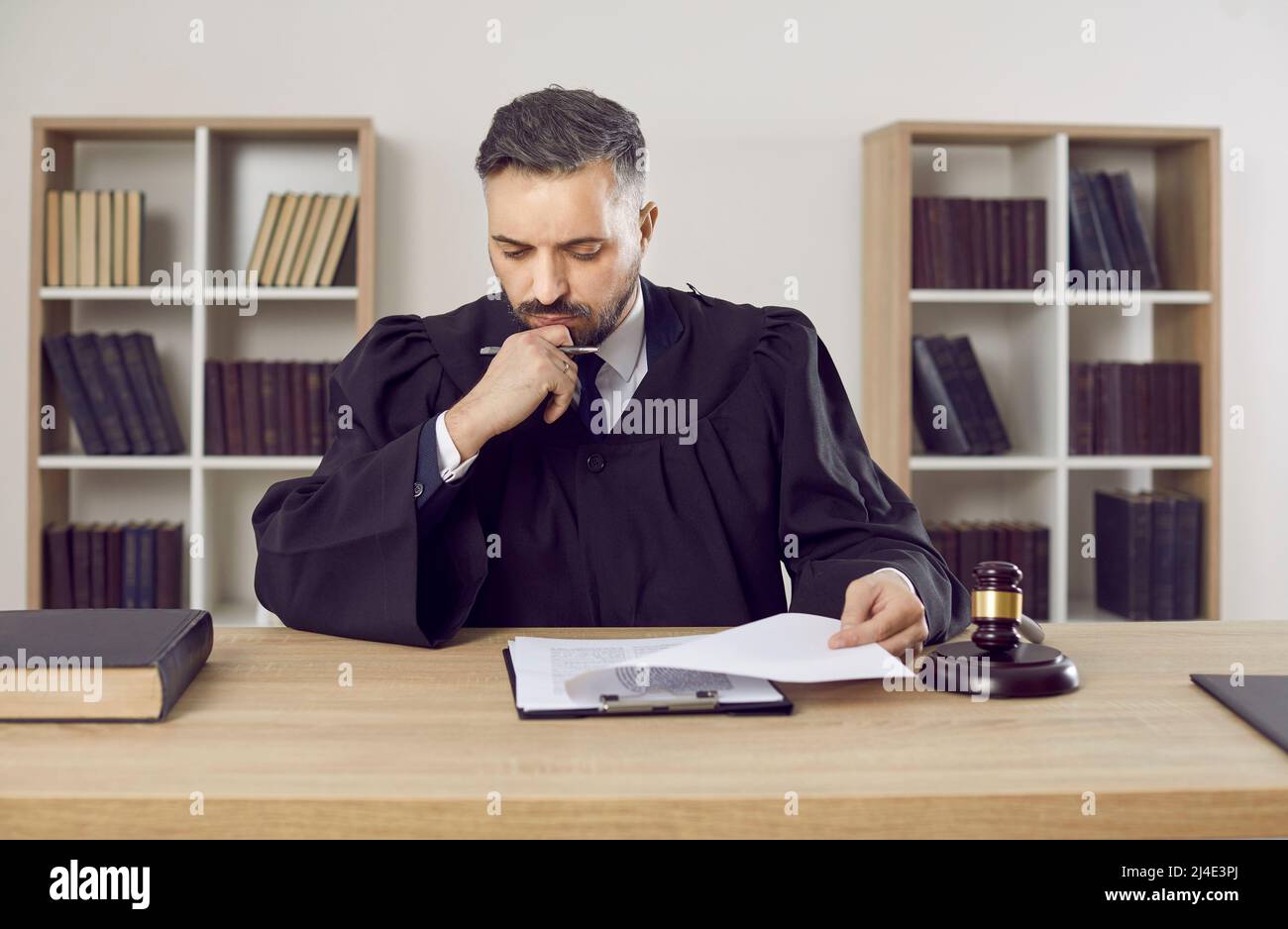 Judge, lawyer or attorney sitting at his table, studying some documents and thinking Stock Photo