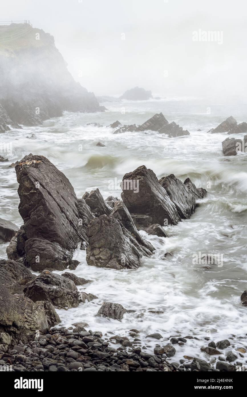 As the tide rises, a layer of drifting mist hides the rugged coastline of Hartland Point in North Devon. Stock Photo