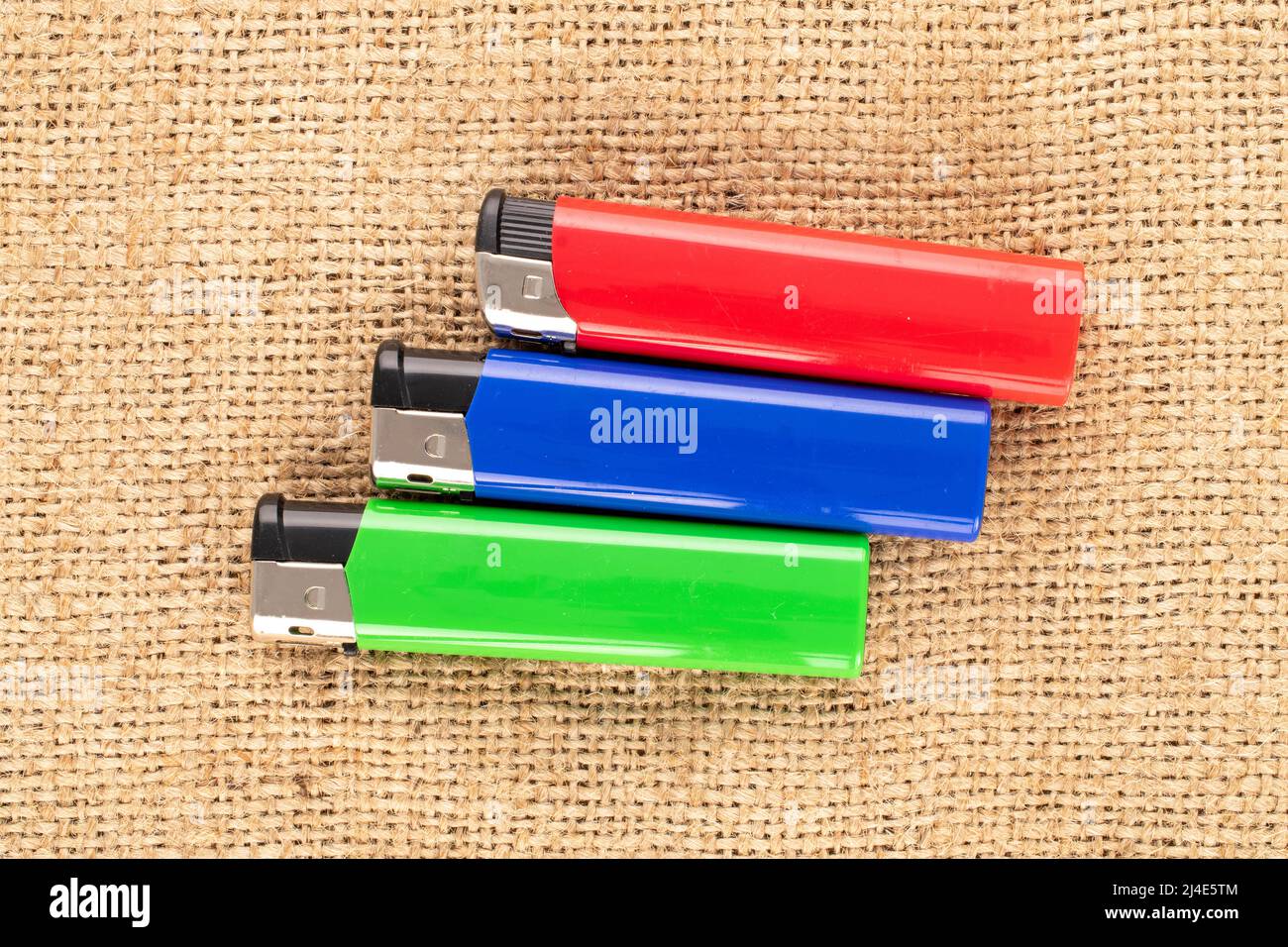 Three colored lighters on jute fabric, macro, top view Stock Photo Alamy