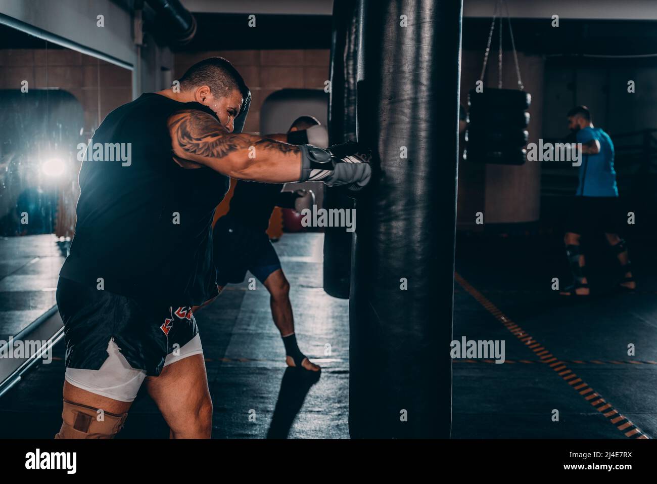 Heavy male kick boxer hitting a huge punching bag at a boxing studio. Man boxer training hard