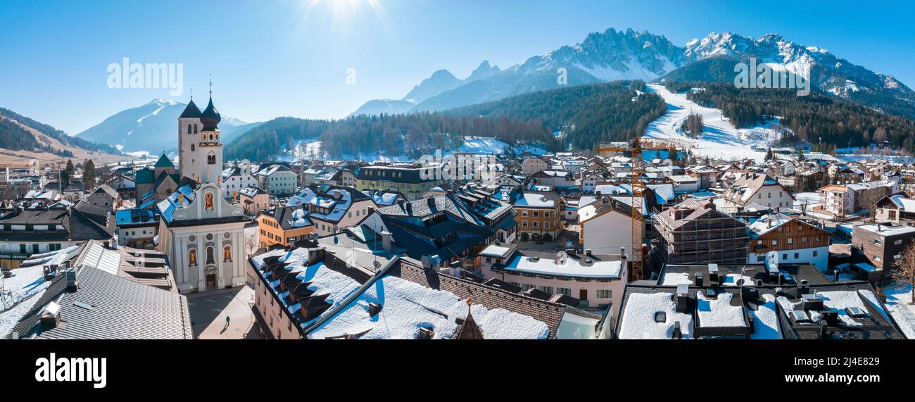 Panoramic view of town against mountains on sunny day during winter Stock Photo