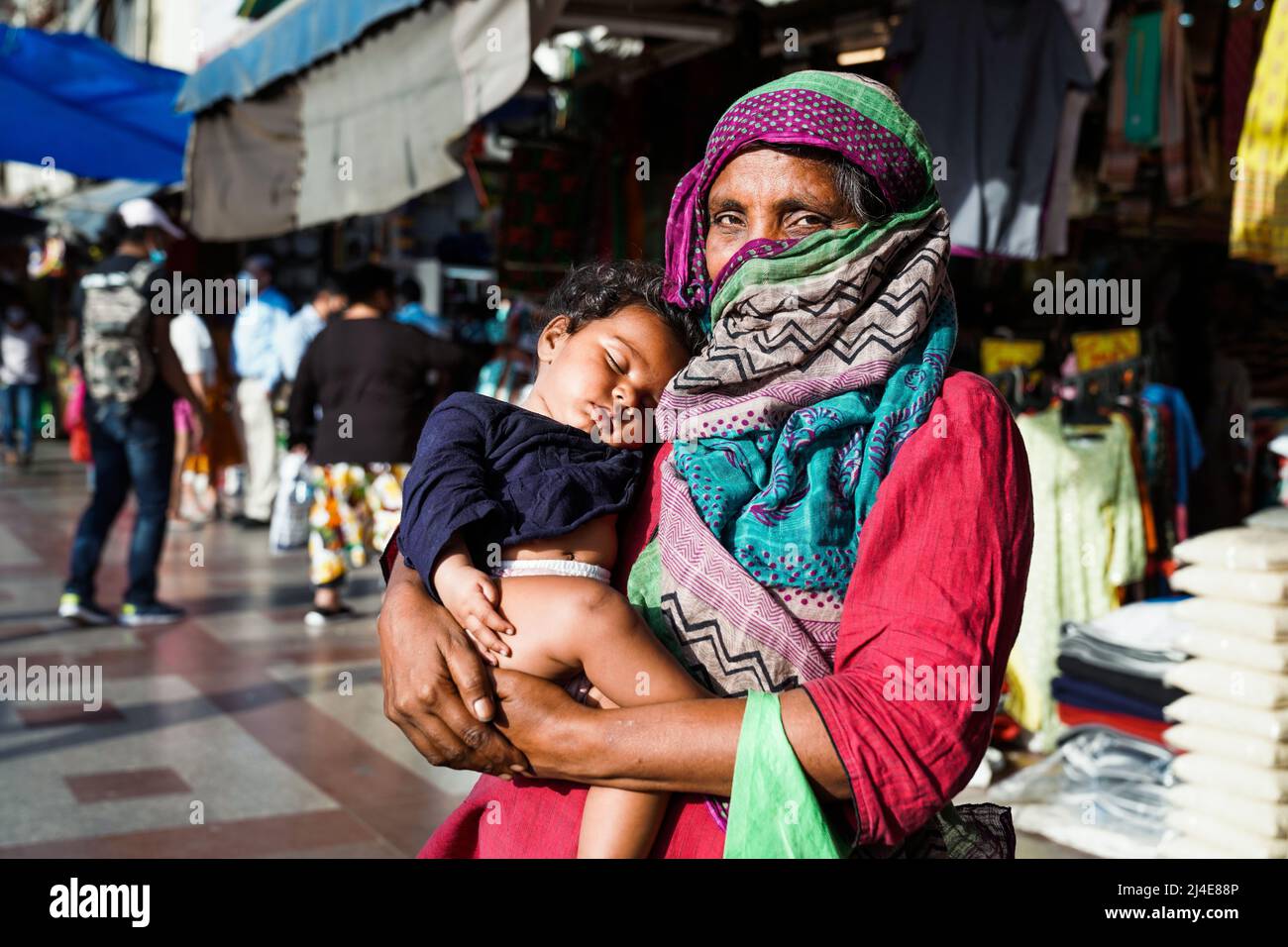 Old indian beggar woman with baby begs the alms in the street of New Delhi, India Stock Photo