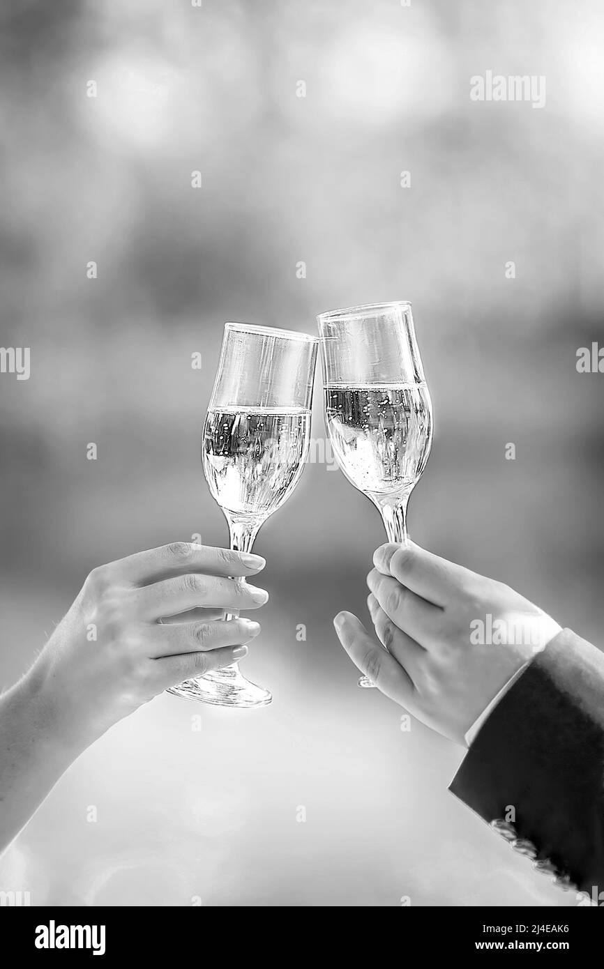 Two glasses of sparkling champagne in hand, a concept for a holiday, bokeh, in a restaurant or outdoors. Women's and men's hands hold champagne glasse Stock Photo