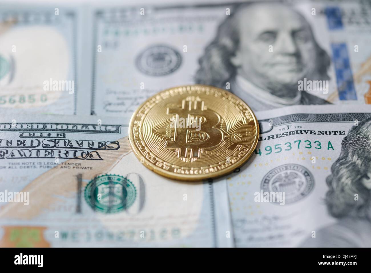 Golden shiny bitcoin crypto currency coins on one hundred US dollar bills. Difference between cryptocurrencies and cash Stock Photo