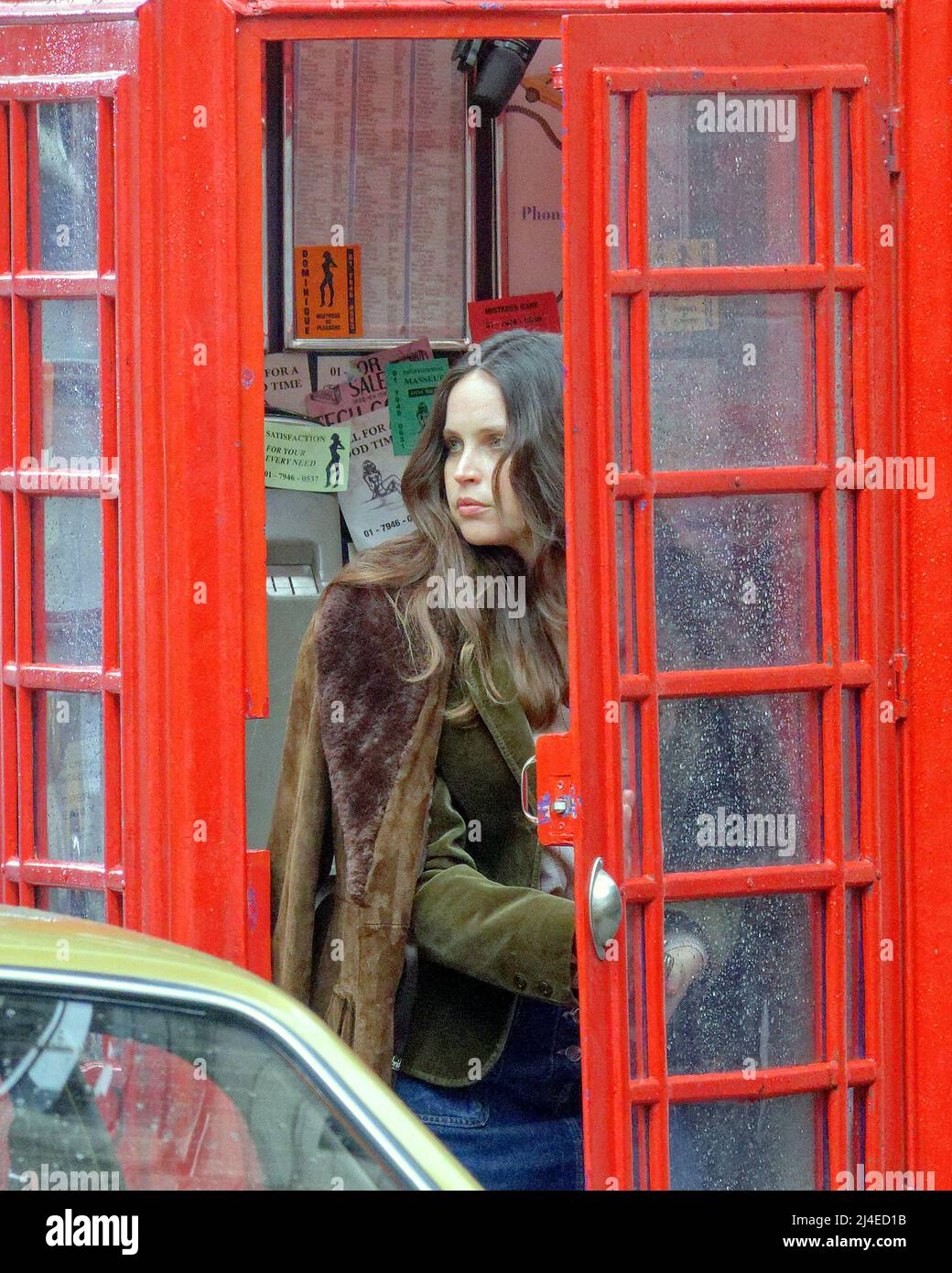 Glasgow, Scotland, UK 14th April, 2022 Hollywood comes to the city again to the tune of have you seen miss jones as Felicity Jones filming in the city saw a very sparkly set of eyes as she looked every inch a film star amongst the drab seventies London set that is Glasgow..  She is seen leaving the famous glasgow pub the griffin and heading to and  phoning from a red phone box. Credit Gerard Ferry/Alamy Live News Stock Photo