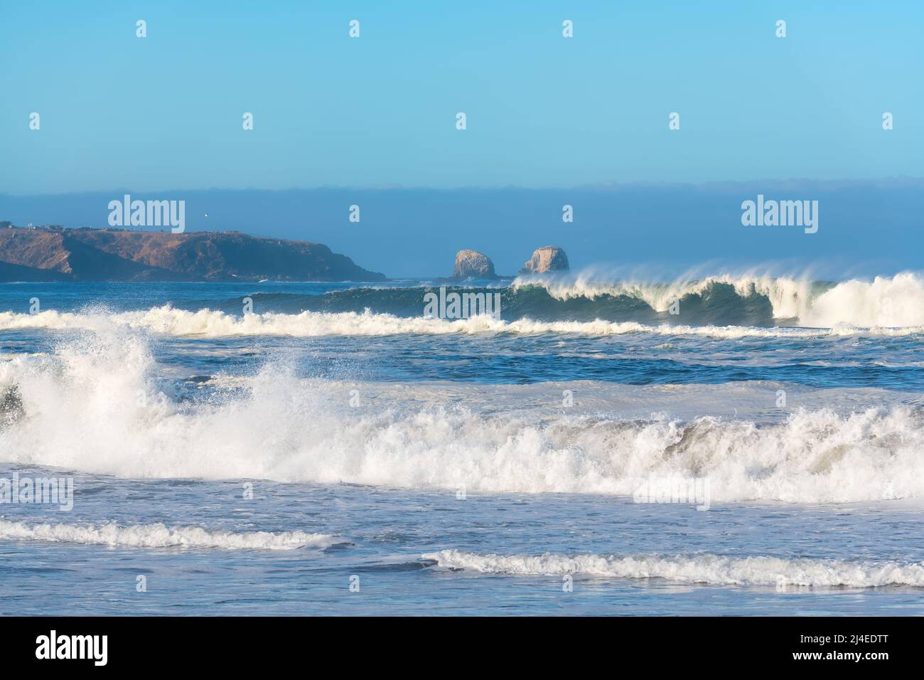 Waves braking in the beach of Pichilemu with the cliffs of Punta de Lobos in the back, VI Region, Chile Stock Photo