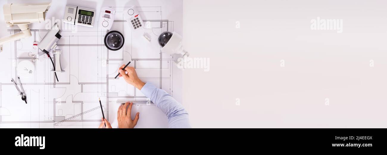 Various Security Equipment In Front Of Two Architects Planning Project On Blueprint Stock Photo
